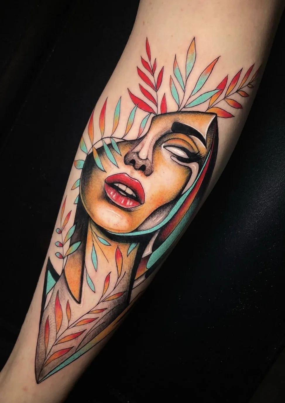 Tatouage coloré représentant un visage entouré de feuillages, par Leali Tattoo